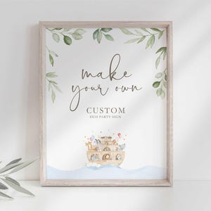 A framed 8x10 custom Noah's Ark party sign rests against a white wall with foliage and watercolor animal illustrations.