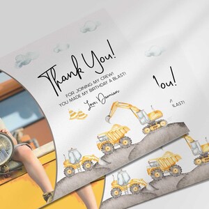Angled close-up of Damian's construction-themed thank you photo card with the boy's photo mockup, showing the dump truck and excavator illustrations with the thank you message.