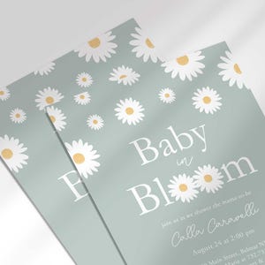 Close-up angled shot of the 'Baby in Bloom' daisy-themed invitation for Calla Caravelli in sage green, showing the print quality and daisy pattern detail.