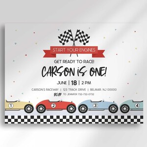 "Carson is ONE!" race car birthday invitation with checkered flags, a red "Start Your Engines" banner, and a row of colorful cartoon race cars.