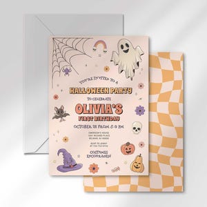 Olivia's Halloween-themed first birthday invitation layered in front of its matching envelope and a second card showing an orange checkerboard back design.