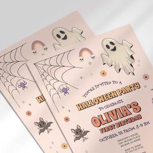 Angled close-up of Olivia's Halloween-themed first birthday invitation, showing the ghost, spiderweb, and bat illustrations with party details.