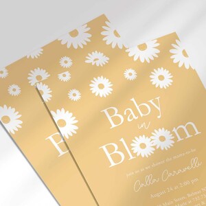 Close-up angled stack of two prints of the 'Baby in Bloom' daisy-themed invitation for Calla Caravelli, showing the print quality and daisy pattern detail.