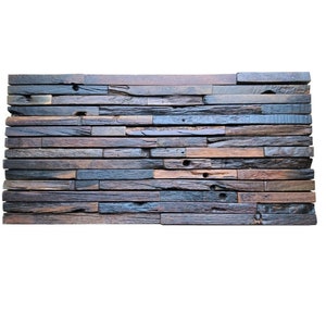 Può includere: Un pannello murale rettangolare realizzato con assi di legno di recupero. Le assi sono disposte orizzontalmente, mostrando un mix di tonalità marroni, grigie e blu. Il legno ha un aspetto invecchiato con nodi e imperfezioni visibili, che aggiungono fascino rustico.