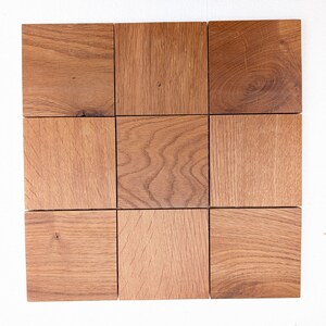 May include: Nine square wooden tiles arranged in a grid. The tiles are a warm brown colour with visible wood grain and texture. The tiles are likely for a home decor project or craft.