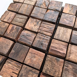 Könnte beinhalten: Eine Nahaufnahme einer Holz-Wandfliese aus kleinen, quadratischen Holzstücken. Die Fliesen sind in einem Rastermuster angeordnet und haben ein rustikales, natürliches Aussehen.