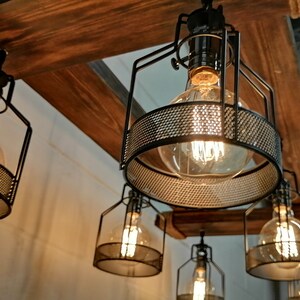 May include: A set of five black metal cage pendant lights with clear glass bulbs. The lights are hanging from a wooden beam.