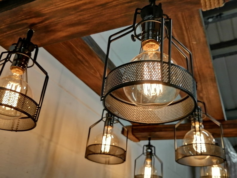 May include: A set of five black metal cage pendant lights with clear glass bulbs. The lights are hanging from a wooden beam.