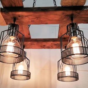 May include: A rustic wooden chandelier with four black metal cage light fixtures. The chandelier is suspended from a chain and has a rope detail on the top.