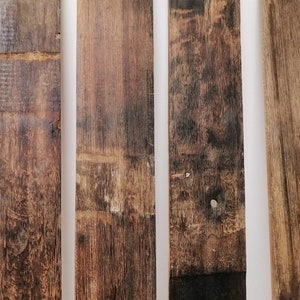 Könnte beinhalten: Vier verwitterte Holzbretter in natürlicher brauner Farbe mit rauer Textur. Die Bretter sind vertikal angeordnet und vor einem weißen Hintergrund platziert.