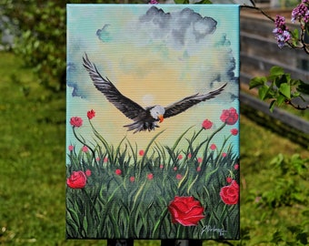 May include: An acrylic painting on canvas depicts a bald eagle in flight over a field of red roses and tall green grass. The background features a cloudy sky with a setting sun. The painting is signed "J. Delmar 24".