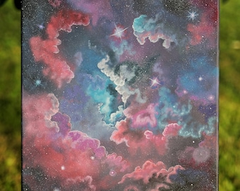 May include: An original acrylic painting of a nebula, featuring swirling clouds of red, pink, blue, and purple against a dark, starry background. The artwork includes several bright, white stars and a signature in the bottom right corner.