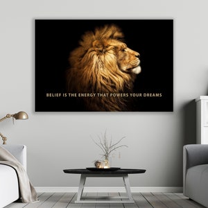 Pode incluir: Uma cita&ccedil;&atilde;o motivacional, "BELIEF IS THE ENERGY THAT POWERS YOUR DREAMS", &eacute; exibida em um fundo preto com a cabe&ccedil;a de um le&atilde;o dourado de perfil.