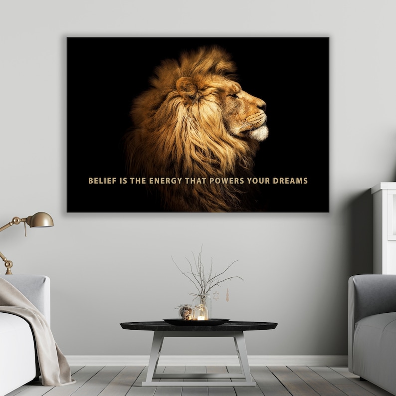 Pode incluir: Uma cita&ccedil;&atilde;o motivacional, "BELIEF IS THE ENERGY THAT POWERS YOUR DREAMS", &eacute; exibida em um fundo preto com a cabe&ccedil;a de um le&atilde;o dourado de perfil.