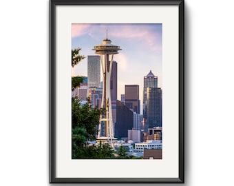 May include: A view of the Seattle skyline with the Space Needle in the center, surrounded by other skyscrapers. The sky is a soft pink and purple, and there are trees in the foreground.