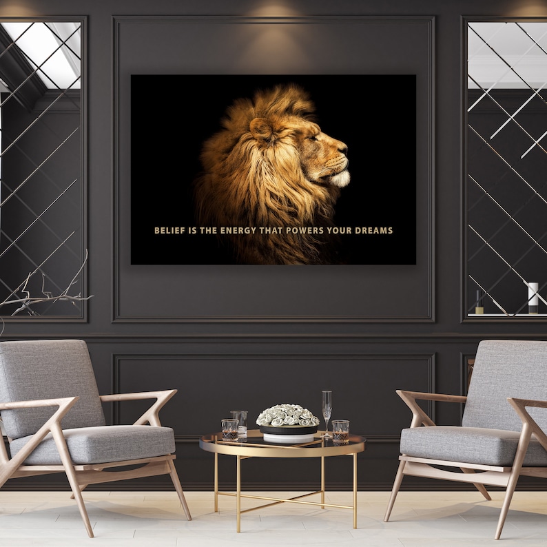 Pode incluir: Uma cita&ccedil;&atilde;o motivacional, "BELIEF IS THE ENERGY THAT POWERS YOUR DREAMS", &eacute; exibida em um fundo preto com um perfil de cabe&ccedil;a de le&atilde;o dourado.