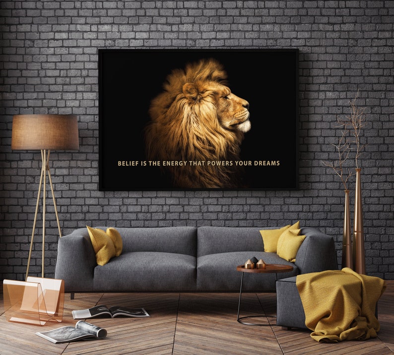 Pode incluir: Uma impress&atilde;o em tela emoldurada em preto com uma cita&ccedil;&atilde;o motivacional, "BELIEF IS THE ENERGY THAT POWERS YOUR DREAMS." A impress&atilde;o apresenta um close-up de uma cabe&ccedil;a de le&atilde;o com uma juba dourada sobre um fundo preto.