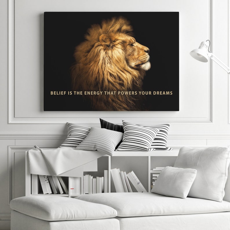 Pode incluir: Uma cita&ccedil;&atilde;o motivacional, "BELIEF IS THE ENERGY THAT POWERS YOUR DREAMS", &eacute; exibida em letras douradas sobre um fundo preto. Um le&atilde;o majestoso com uma juba espessa &eacute; mostrado de perfil, olhando para a direita.