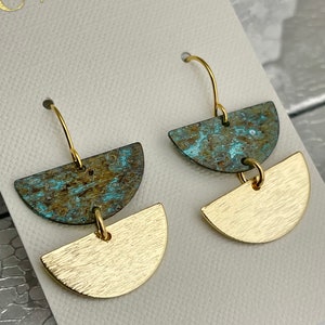 May include: A pair of gold earrings with a geometric design. The top half of each earring is a half-circle of turquoise and brown metal, and the bottom half is a gold half-circle.