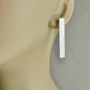 May include: A pair of silver bar earrings with a textured finish.