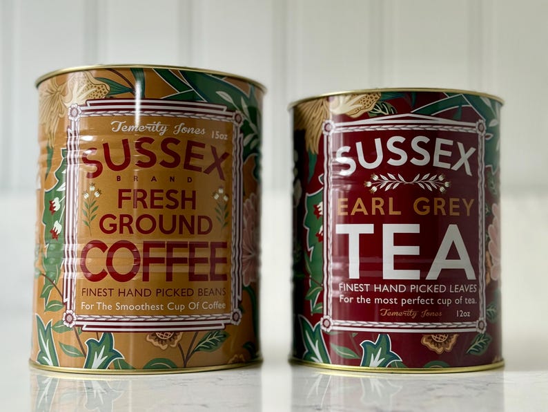 May include: Two decorative metal tins of Sussex Brand coffee and tea. The coffee tin is tan with red text and floral accents. The tea tin is red with white text and floral accents. Both tins have gold rims and are labeled with the brand name and product type.