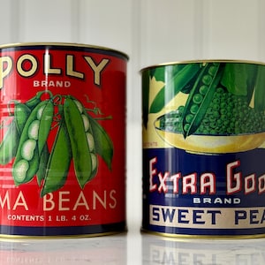 May include: Two vintage-style cans of vegetables. One is red with "POLLY BRAND LIMA BEANS" and a graphic of lima beans. The other is green and blue with "EXTRA GOOD BRAND SWEET PEAS" and a pea pod graphic. Each can is 1 lb 4 oz.