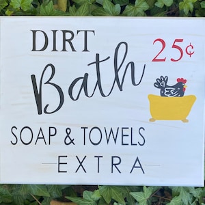 May include: White wooden sign with black text that reads "Dirt Bath 25¢ Soap & Towels -EXTRA-". A black chicken is sitting in a yellow bathtub.