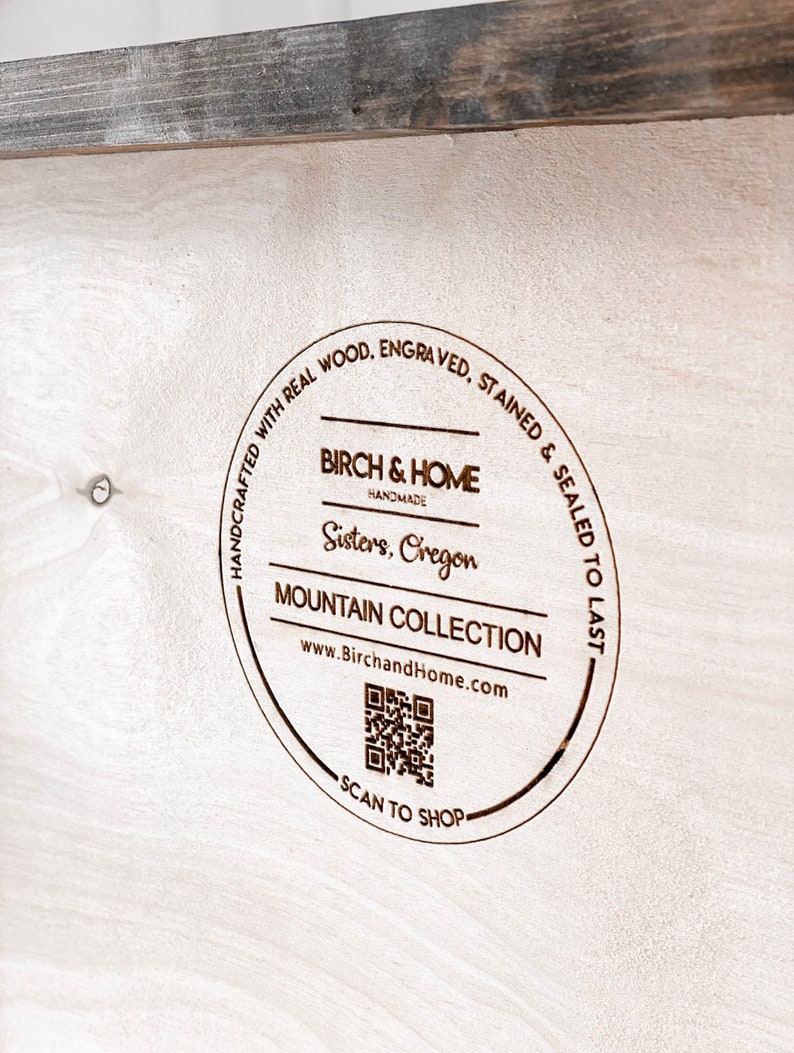 Puede incluir: Un letrero redondo de madera con el texto "HANDCRAFTED WITH REAL WOOD. ENGRAVED. STAINED & SEALED TO LAST" que rodea un logotipo que dice "BIRCH & HOME HANDMADE Sisters, Oregon MOUNTAIN COLLECTION www.BirchandHome.com" con un c&oacute;digo QR y el texto "SCAN TO SHOP".