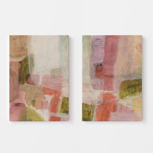 May include: A set of two rectangular wall art canvases featuring abstract compositions. The paintings display layered brushstrokes in muted shades of dusty rose, soft peach, olive green, and cream, with thin graphite lines intersecting the color blocks.