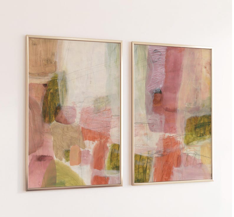 May include: Two rectangular wall art prints in thin gold frames featuring abstract compositions. The artwork displays layered washes of muted pink, soft orange, olive green, and cream tones with visible brushstrokes and thin charcoal lines.