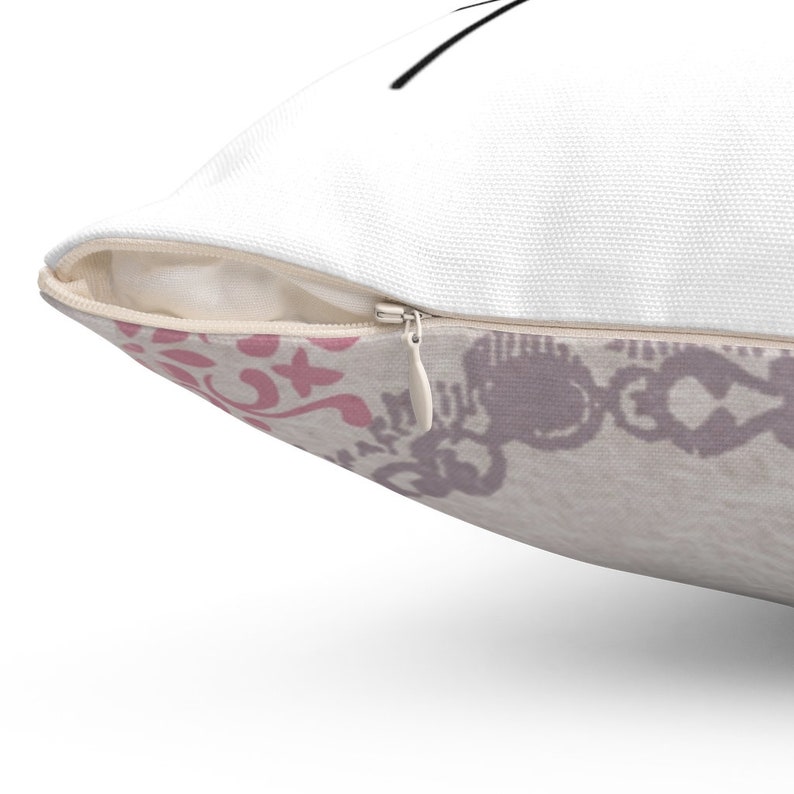 Puede incluir: Una almohada blanca con cierre de cremallera. La almohada tiene un patr&oacute;n floral rosa y gris en la parte posterior.
