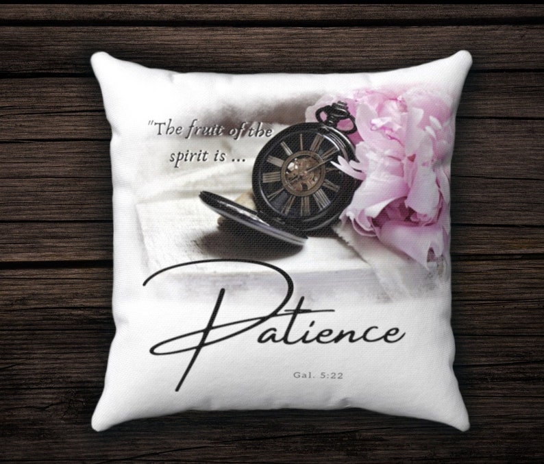 Puede incluir: Almohada blanca con una cita sobre la paciencia, "El fruto del esp&iacute;ritu es... Paciencia, G&aacute;l. 5:22". La cita est&aacute; acompa&ntilde;ada de un reloj de bolsillo vintage y una flor rosa.