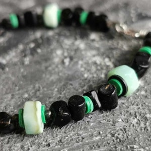 May include: A black and green beaded bracelet with a silver clasp. The beads are made of black onyx and green jade.