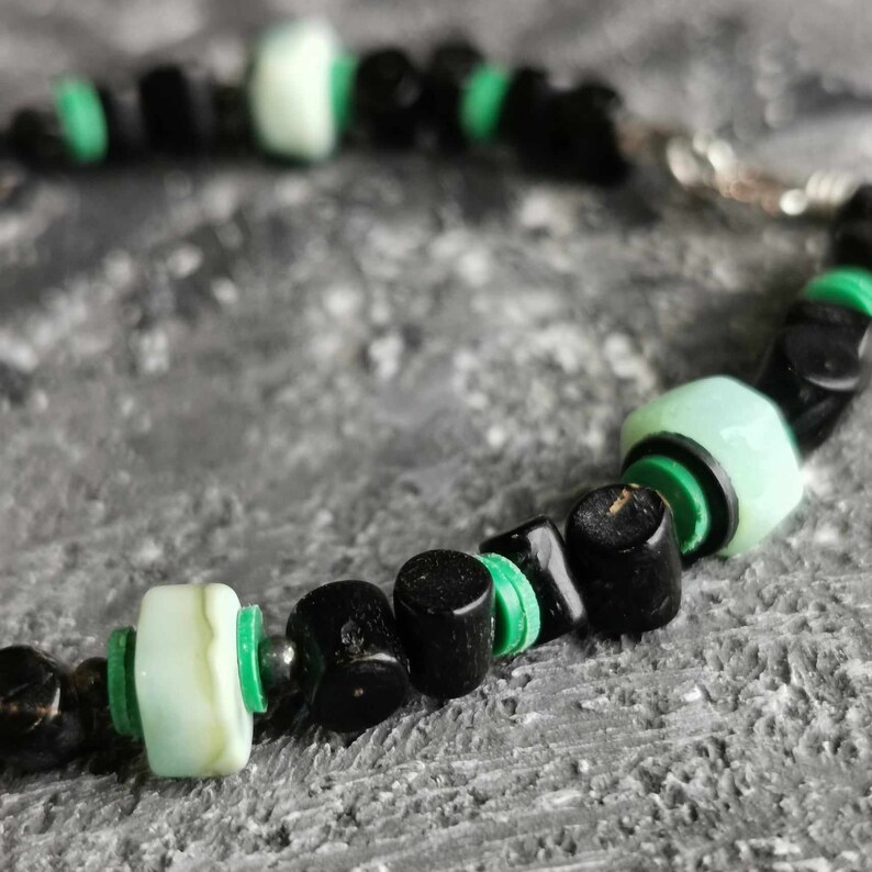 May include: A black and green beaded bracelet with a silver clasp. The beads are made of black onyx and green jade.