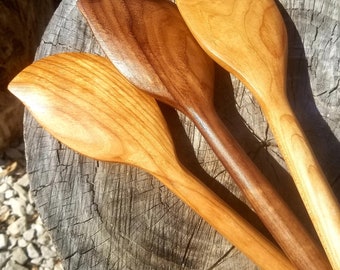 May include: Three wooden spoons with leaf-shaped bowls. The spoons are made of different types of wood, with one being a darker brown and the other two being a lighter brown.