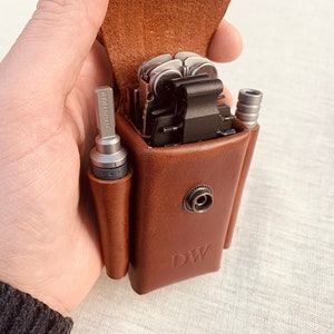 May include: A brown leather case with a snap closure and the initials "DW" embossed on the front. The case holds a multi-tool and two small tools.