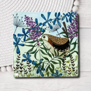 May include: A watercolour painting of a brown and white bird perched on a green branch with blue flowers and green leaves. The background is a light blue watercolour wash.