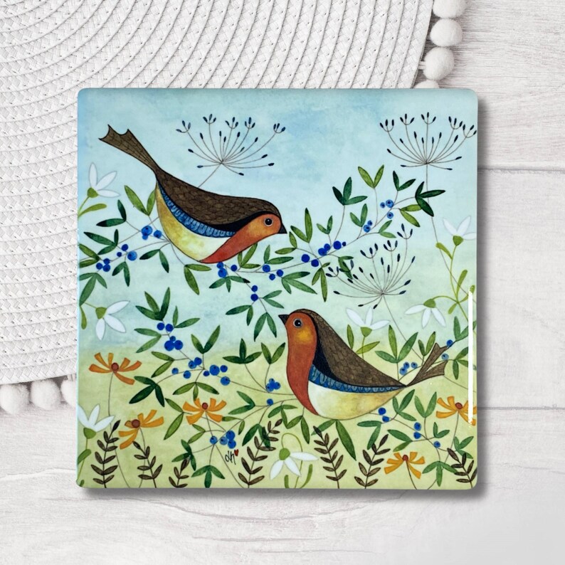 May include: Two brown and orange birds with blue accents are perched on green branches with blue berries. The birds are facing each other and are surrounded by green leaves and white flowers against a light blue background.