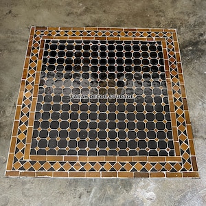 May include: A black and gold Moroccan tile floor with a geometric pattern. The tile floor has a border of gold tiles with a diamond pattern. The text "FARAH DECOR SOUDAGE" is visible in the centre of the floor.