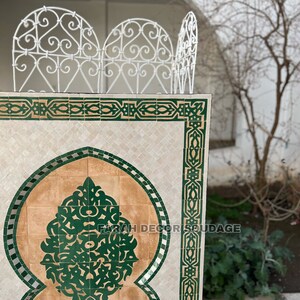 Puede incluir: Una fuente tradicional marroqu&iacute; con intrincados azulejos verdes y marrones. La fuente presenta un arco decorativo y un peque&ntilde;o ca&ntilde;o. El texto "FARAH DECOR SOUDAGE" es visible en la fuente.