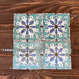 Peut inclure: Quatre carreaux de céramique carrés avec un motif floral bleu, vert et blanc. Les carreaux sont disposés en grille 2x2. Le texte "FARAH DECOR SOUDAGE" est visible sur l'image.