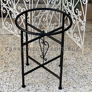 Puede incluir: Soporte de metal negro con parte superior redonda y un dise&ntilde;o decorativo de volutas. El soporte tiene un dise&ntilde;o simple y elegante y ser&iacute;a perfecto para exhibir plantas u otros art&iacute;culos decorativos.