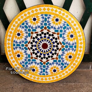 May include: A round, yellow, blue, and white mosaic tile table top with a geometric pattern. The table top is approximately 30 inches in diameter.