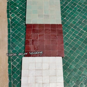 May include: Three square tiles, each with a different color. The top tile is light green, the middle tile is dark red, and the bottom tile is white. The tiles are arranged vertically, with the top tile at the top of the image and the bottom tile at the bottom of the image. The tiles are all made of the same material, and they have a smooth, glossy finish.