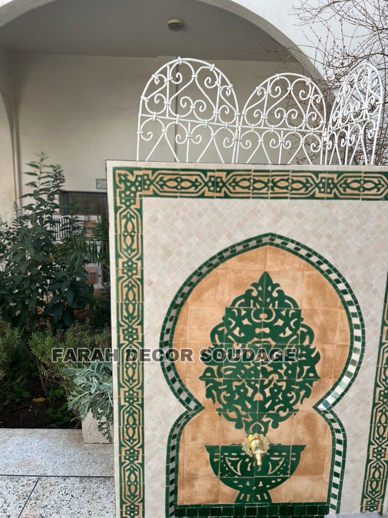 Puede incluir: Una fuente decorativa de azulejos con un dise&ntilde;o de mosaico verde y marr&oacute;n. La fuente presenta un arco tradicional marroqu&iacute; y intrincados patrones florales. El texto "FARAH DECOR SOUDAGE" es visible en la fuente.