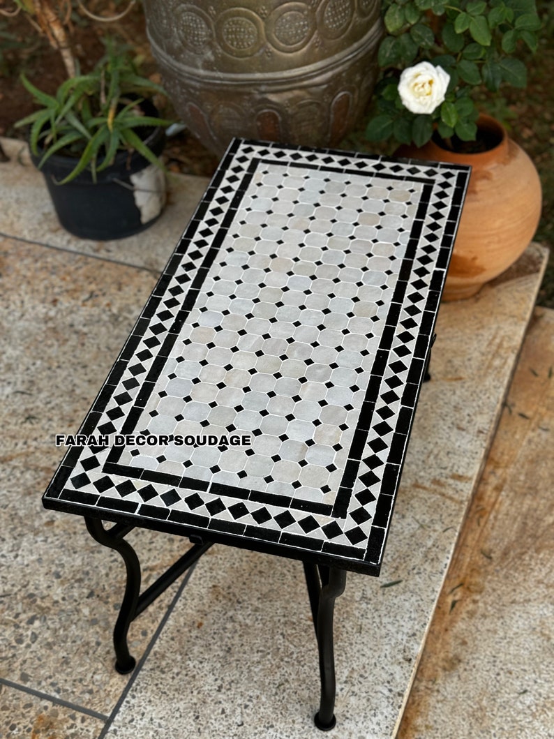 May include: A black and white Moroccan tile top coffee table with a black metal frame. The table has a geometric pattern of black and white squares and diamonds.