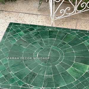 Puede incluir: Una mesa de mosaico verde con un patr&oacute;n circular en el centro. La mesa est&aacute; rodeada por un marco de metal negro. El texto "FARAH DECOR SOUDAGE" es visible en la mesa.
