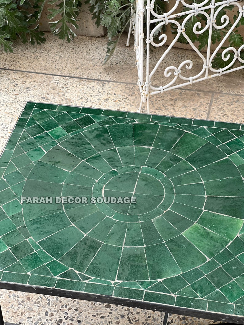 Puede incluir: Una mesa de mosaico verde con un patr&oacute;n circular en el centro. La mesa est&aacute; rodeada por un marco de metal negro. El texto "FARAH DECOR SOUDAGE" es visible en la mesa.