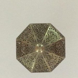 May include: A silver metal lantern with intricate cut-out designs. The lantern is shaped like a pyramid with a pointed top.