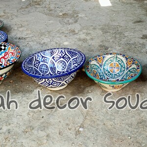 May include: Five ceramic bowls with intricate colourful patterns. The bowls are arranged in a row on a grey concrete surface. The text "Farah decor soudage" is written below the bowls.
